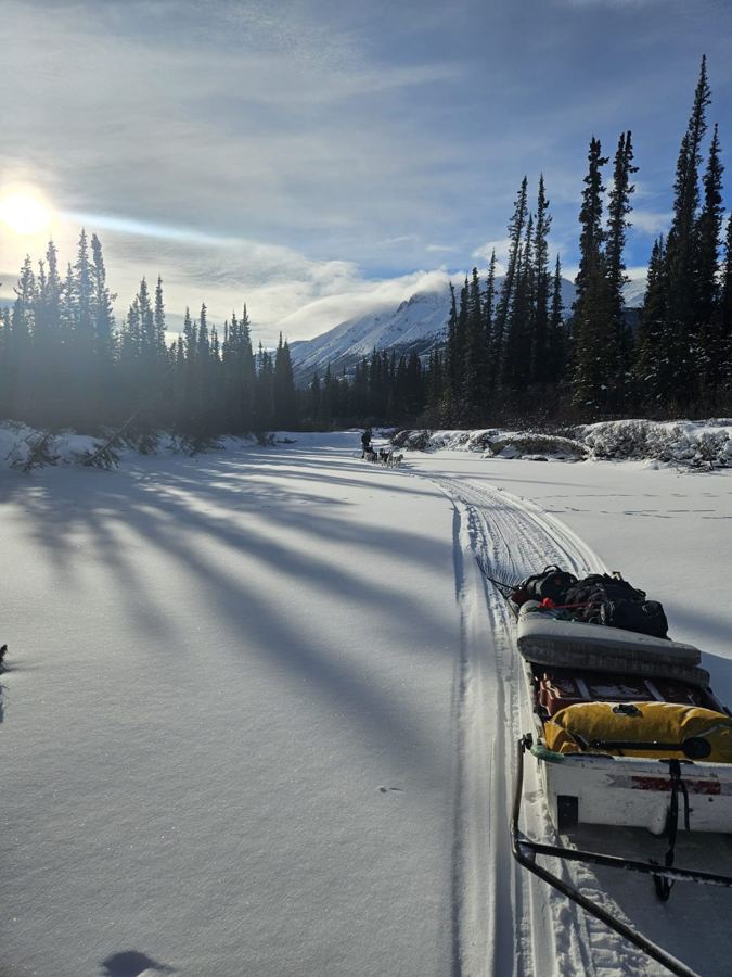 Traîneau d'expédition sur une rivière gelée, face aux montagnes