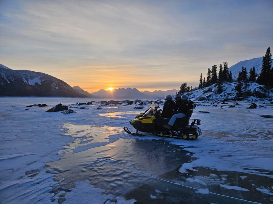 Motoneige au coucher du soleil sur le lac gelé près de Carcross