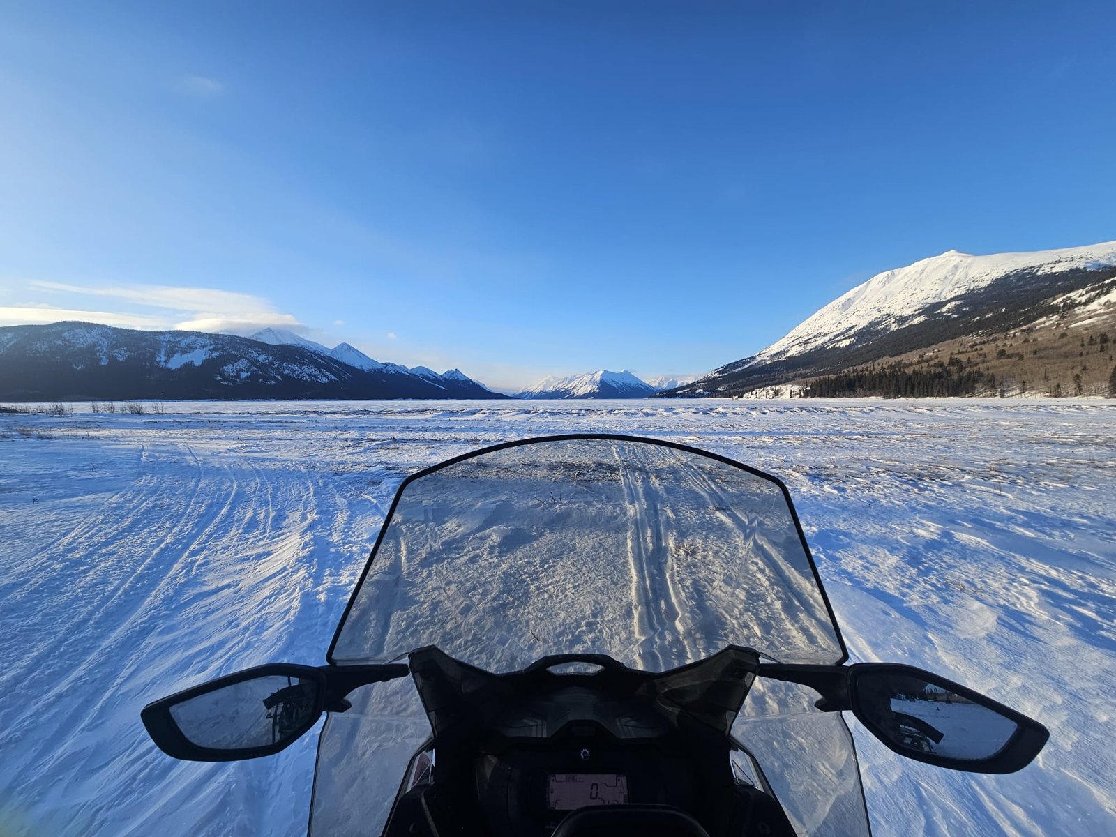 Vue depuis la motoneige sur un lac gelé et les montagnes